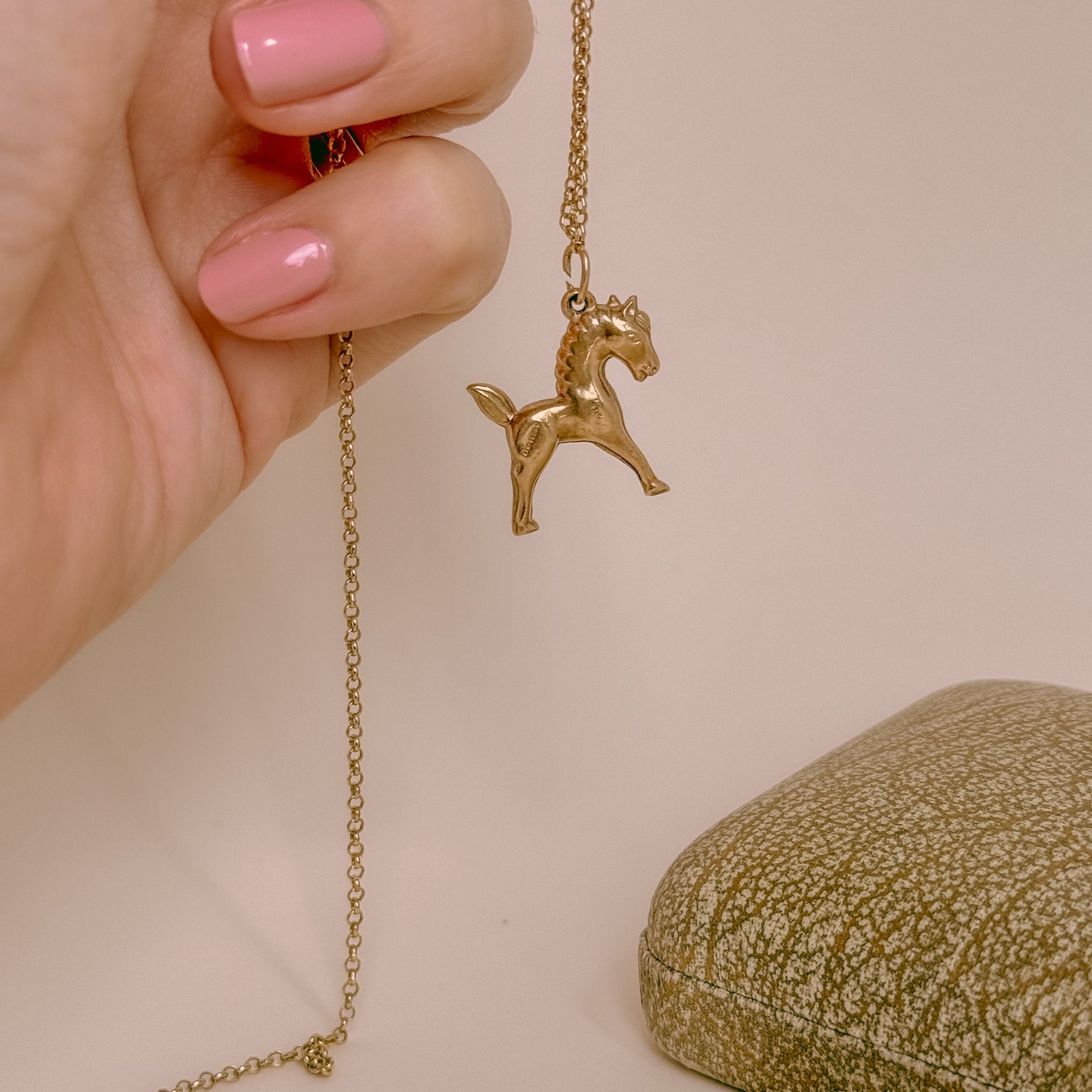 yellow gold horse charm shown on a chain 