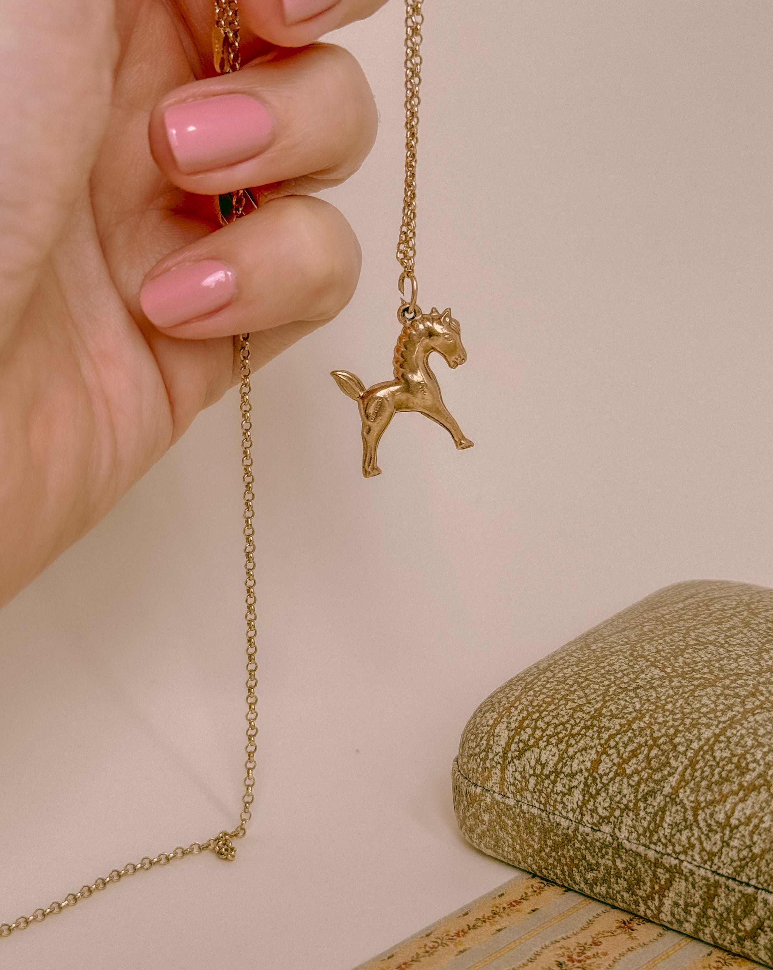 yellow gold horse charm shown on a chain 